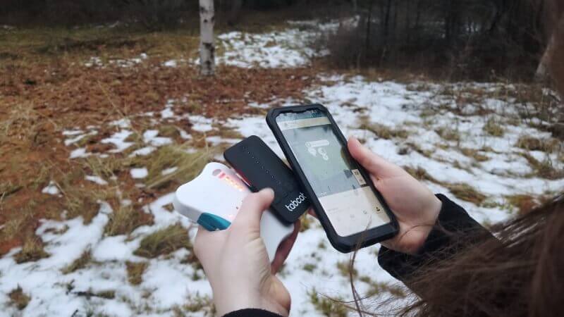 tester holding several cat trackers outside